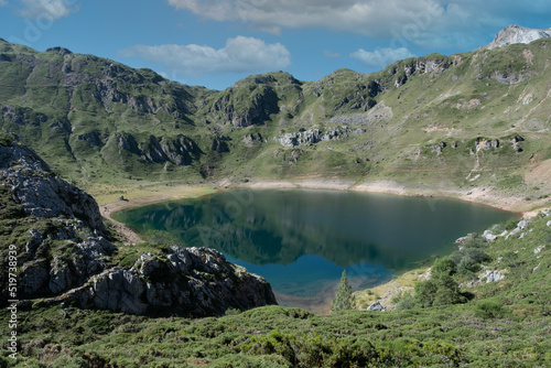 Horizontal shot of beautiful landcsape of a lake surrounded by montains and blue sky with clouds. Location of Asturias, Spain