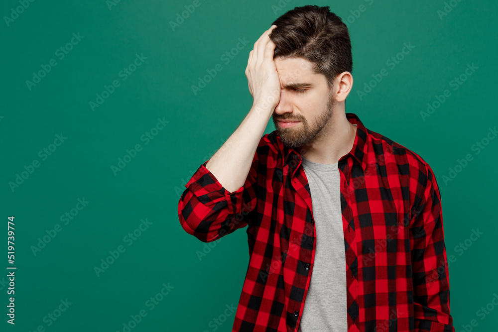 Young sad caucasian man he 20s wearing red shirt grey t-shirt put hand on face facepalm epic fail mistaken omg gesture isolated on plain dark green background studio portrait People lifestyle concept. Young sad caucasian man he 20s wearing red shirt grey t-shirt put hand on face facepalm epic fail mistaken omg gesture isolated on plain dark green background studio portrait People lifestyle concept.