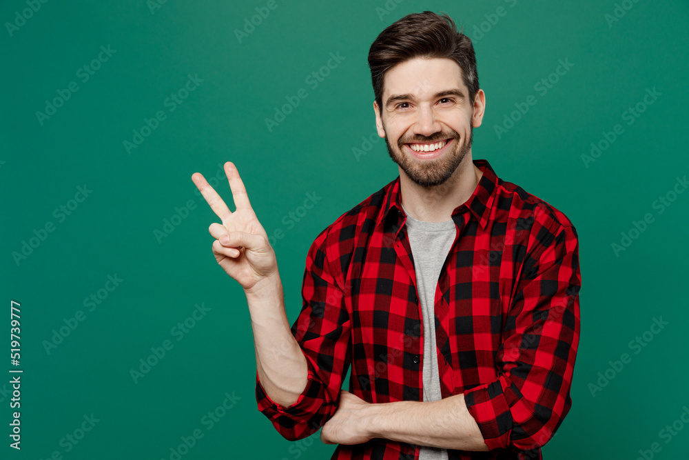 Young happy smiling fun cool caucasian man he 20s wearing red shirt grey t-shirt show victory sign look camera isolated on plain dark green color background studio portrait People lifestyle concept