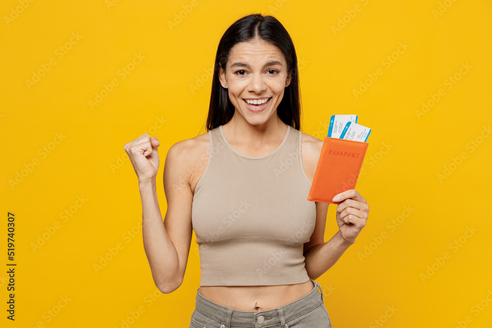Traveler tourist woman wear beige tank shirt hold passport boarding ticket do winner gesture isolated on plain yellow background Passenger travel abroad on weekends getaway Air flight journey concept Traveler tourist woman wear beige tank shirt hold passport boarding ticket do winner gesture isolated on plain yellow background Passenger travel abroad on weekends getaway Air flight journey concept