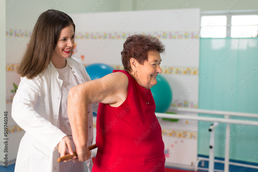 Old senior woman exercising on physical therapy with help of the physiotherapist in the hospital Old senior woman exercising on physical therapy with help of the physiotherapist in the hospital