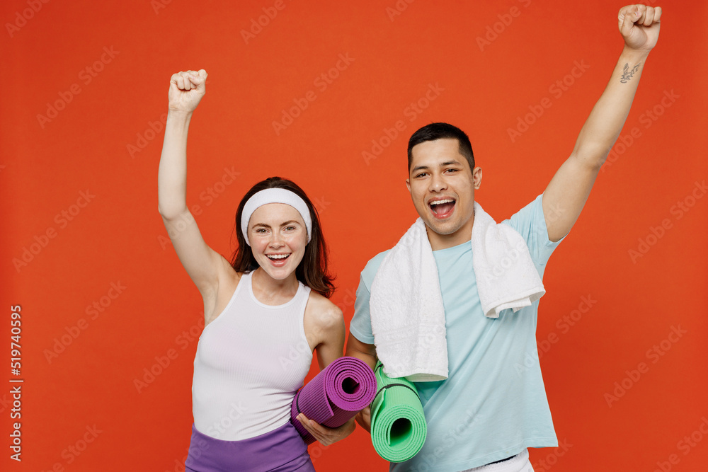Φωτογραφία Young happy fun fitness trainer instructor sporty two man woman in headband t-shirt hold yoga mat do winner gesture spend weekend in home gym isolated on plain orange background Workout sport concept