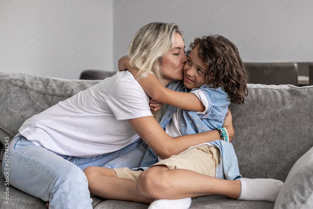 Funny boy child kissing and hugging happy laughing mother parent. Young family mom with son Funny boy child kissing and hugging happy laughing mother parent. Young family mom with son