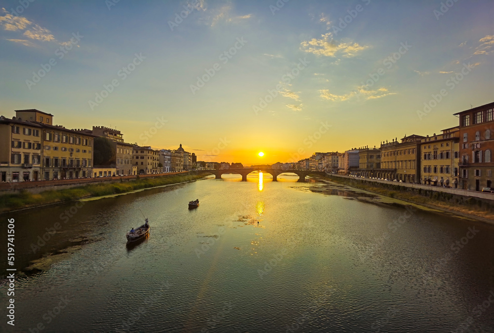 Glimpse of a sunset on the Arno river in Florence, with bridges and boats.
