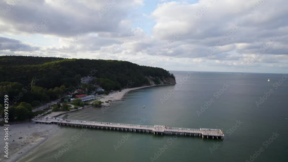 Orlowo pier and public beach coastline on summer cloudy day in Gdynia, Poland - Aerial uprise reversing shot Orlowo pier and public beach coastline on summer cloudy day in Gdynia, Poland - Aerial uprise reversing shot