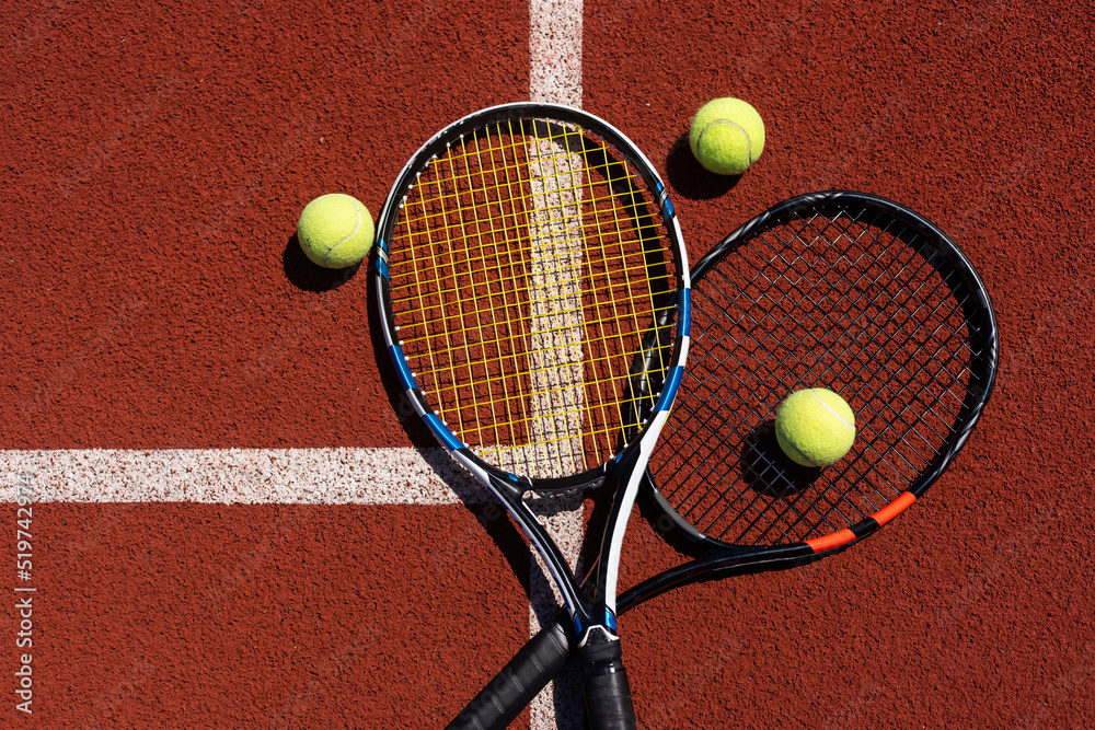 Tennis racquets with tennis balls on clay court.
