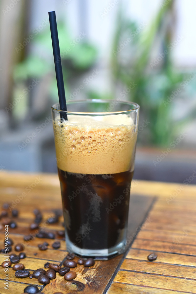 Cold americano with coffee beans  on wooden table