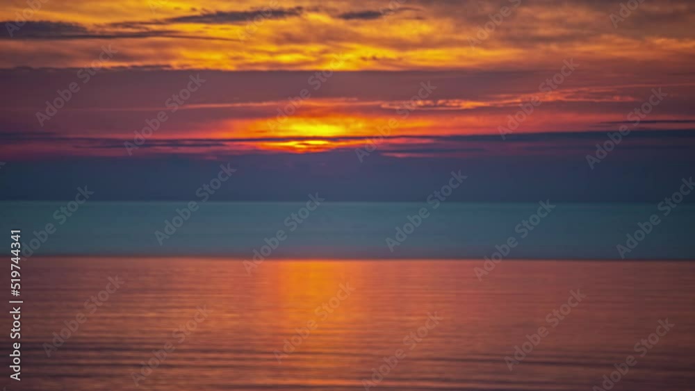 Brilliant sunrise over the ocean with the sky reflecting off the surface of the water - long exposure time lapse Brilliant sunrise over the ocean with the sky reflecting off the surface of the water - long exposure time lapse