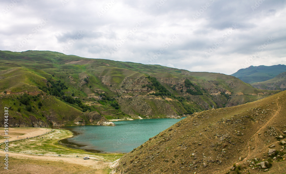 Lake Gizhgit turquoise high in the mountains with hilly shores and a cloudy summer day