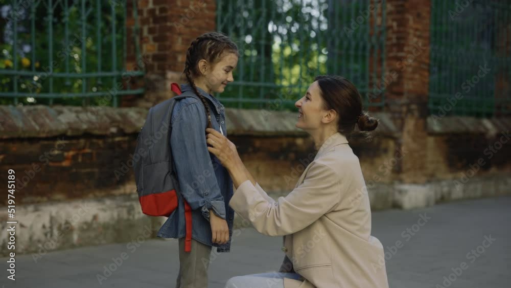 Happy mother escorts child to school. Kid happy dream concept. Girl rushes to lesson back to school. Positive girl talk to mom and hug her. Morning before the school Happy mother escorts child to school. Kid happy dream concept. Girl rushes to lesson back to school. Positive girl talk to mom and hug her. Morning before the school