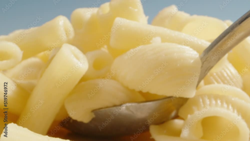 Boiled pasta on a blue sky background. I take them with a spoon, very close-up. Boiled pasta on a blue sky background. I take them with a spoon, very close-up.