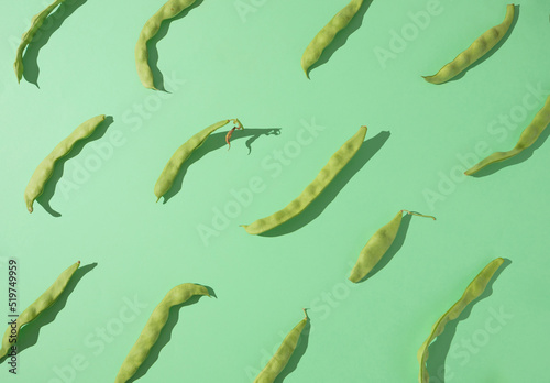 Pattern made of green bean pods on a light pastel green background. Flat lay creative minimal design.