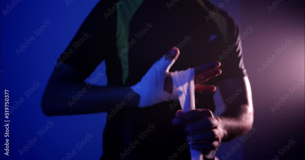 Young male shadow boxing training for a box match putting on gloves and bandages Young male shadow boxing training for a box match putting on gloves and bandages