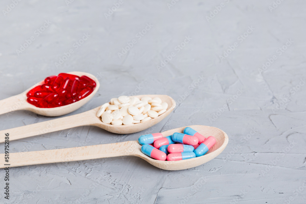 Vitamin capsules in a spoon on a colored background. Pills served as a healthy meal. Red soft gel vitamin supplement capsules on spoon Vitamin capsules in a spoon on a colored background. Pills served as a healthy meal. Red soft gel vitamin supplement capsules on spoon