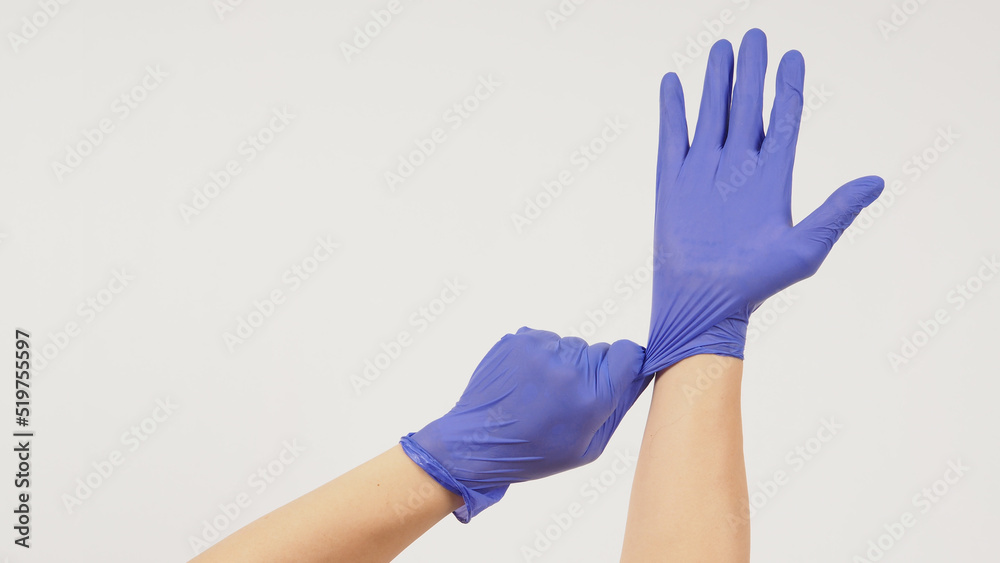 Hand is pulling purple latex gloves on white background. Hand is pulling purple latex gloves on white background.