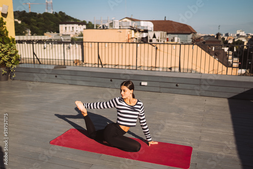 Woman doing yoga exercises on house roof in early morning