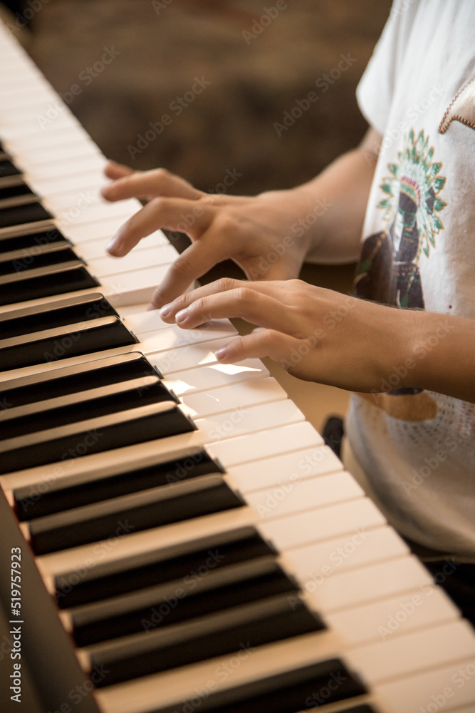 Hands of the child playing piano. Initiation to music, experiences and learning, concept. Closed image and shallow depth of field.