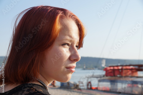 portrait of a teenage red-haired girl squinting from the sun