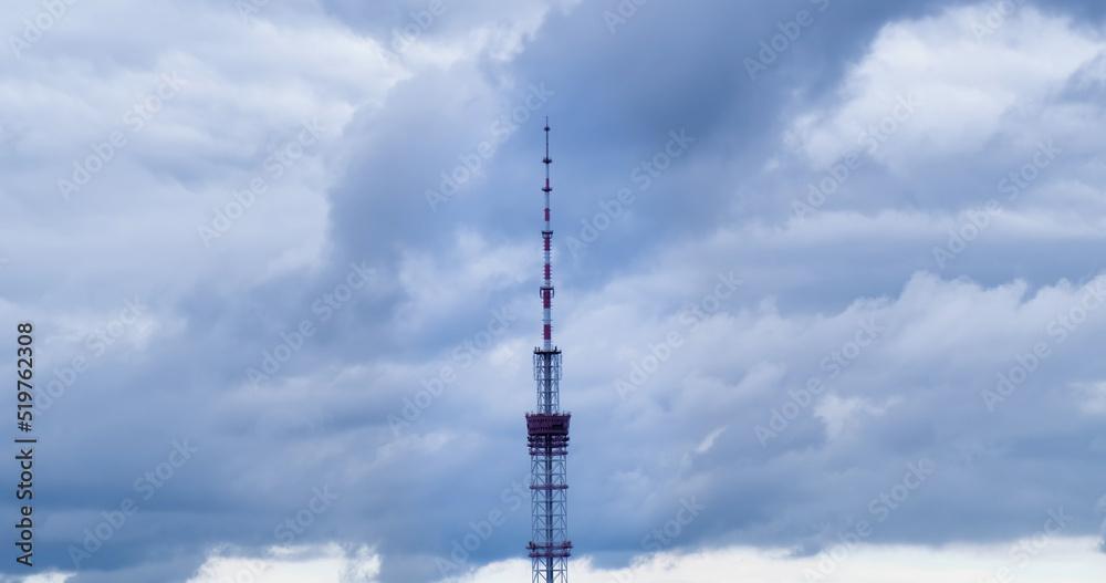 Telecom antenna tower on gray clouds background. TV spit aims at cloudy sky in overcast day. Telecommunication technology broadcasts television signal Telecom antenna tower on gray clouds background. TV spit aims at cloudy sky in overcast day. Telecommunication technology broadcasts television signal