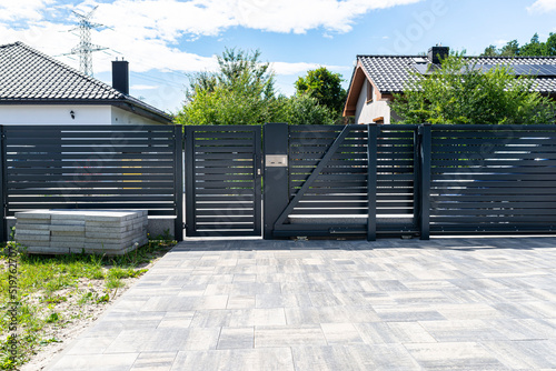 A modern panel fence in anthracite color, a visible sliding gate to the garage and a wicket with a letterbox. photo