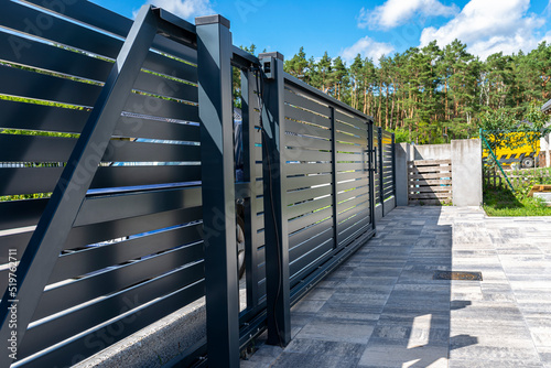 Modern panel fencing in anthracite color, visible sliding gate to the garage as well as a handle and a lock. photo