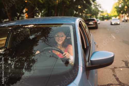 Beautiful Smiling woman driving car, girl sitting in automobile photo