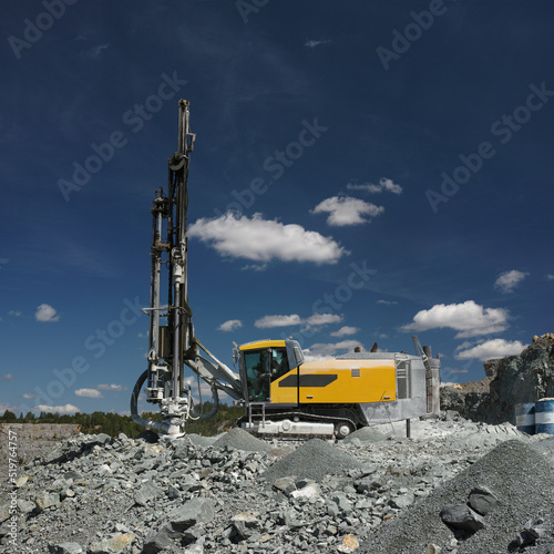 Drilling machine in a stone quarry on the background of blue sky with clouds, close-up, panorama. Quarry mining machinery.