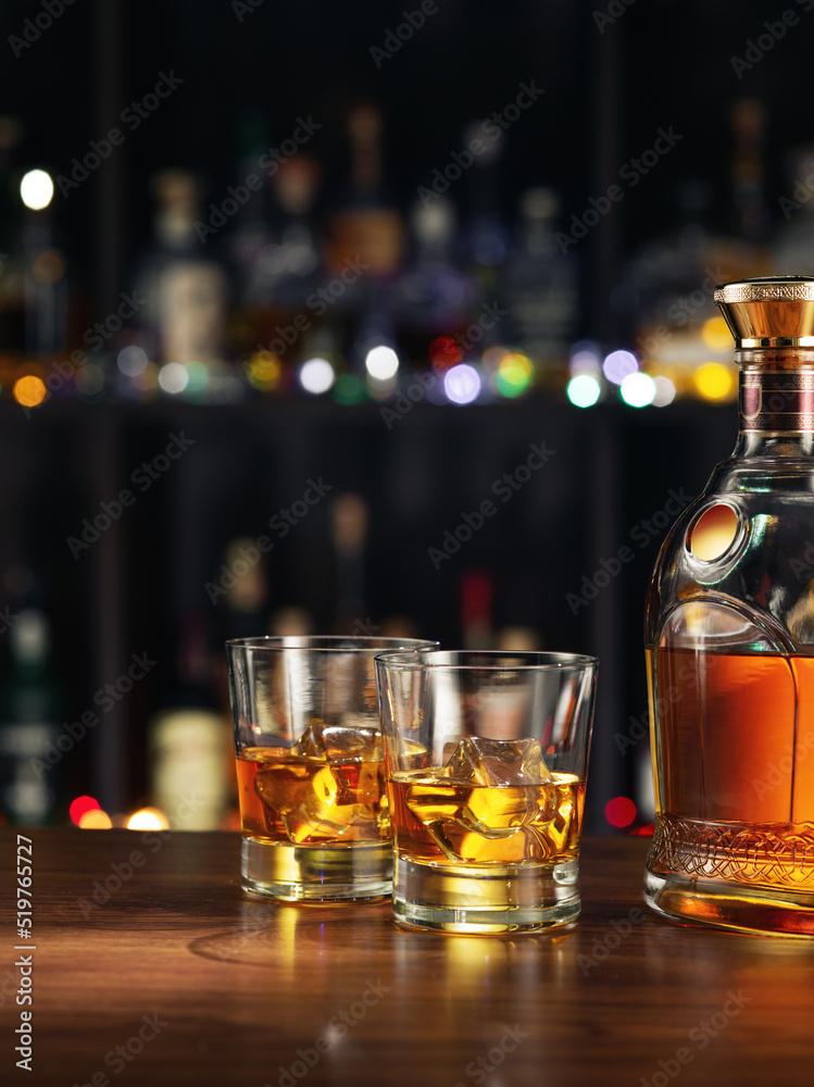 close up view of bottle of whiskey and glasses aside on color back. close up view of bottle of whiskey and glasses aside on color back.