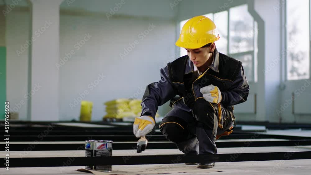 Charismatic woman constructor worker working concentrated at construction site she using a painting brush to painting the building materials and wearing protective helmet and uniform Charismatic woman constructor worker working concentrated at construction site she using a painting brush to painting the building materials and wearing protective helmet and uniform