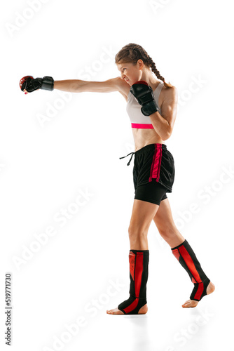 One sportive teen-girl, professional MMA fighter practicing punch isolated on white background. Concept of sport, competition, action, healthy lifestyle.