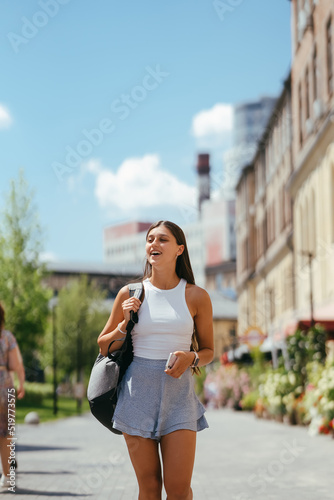 Young woman with backpack walks around the city.