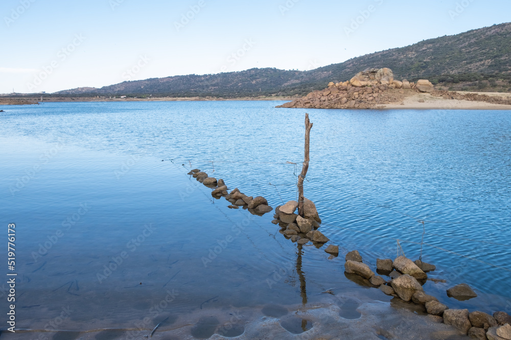 Obraz premium A submerged and weathered barbed wire fence enters the water of a lake.