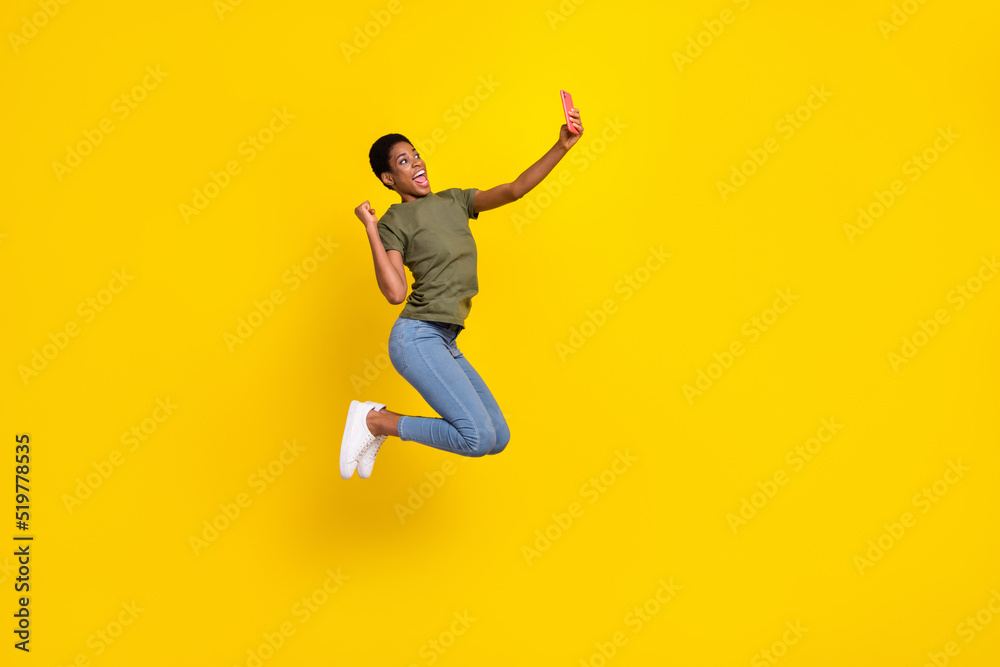 Full size photo of delighted excited person raise fist jump take selfie photo isolated on yellow color background