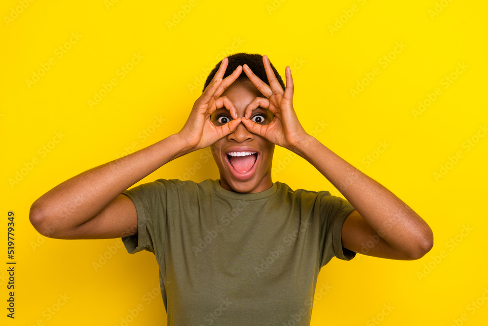 Portrait of carefree funky person arms fingers make binoculars isolated on yellow color background Portrait of carefree funky person arms fingers make binoculars isolated on yellow color background