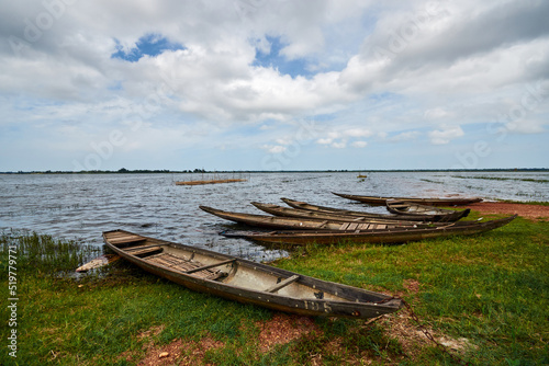 several fishing boats on the shore. wooden boats are pulled ashore with green grass. sky with white clouds