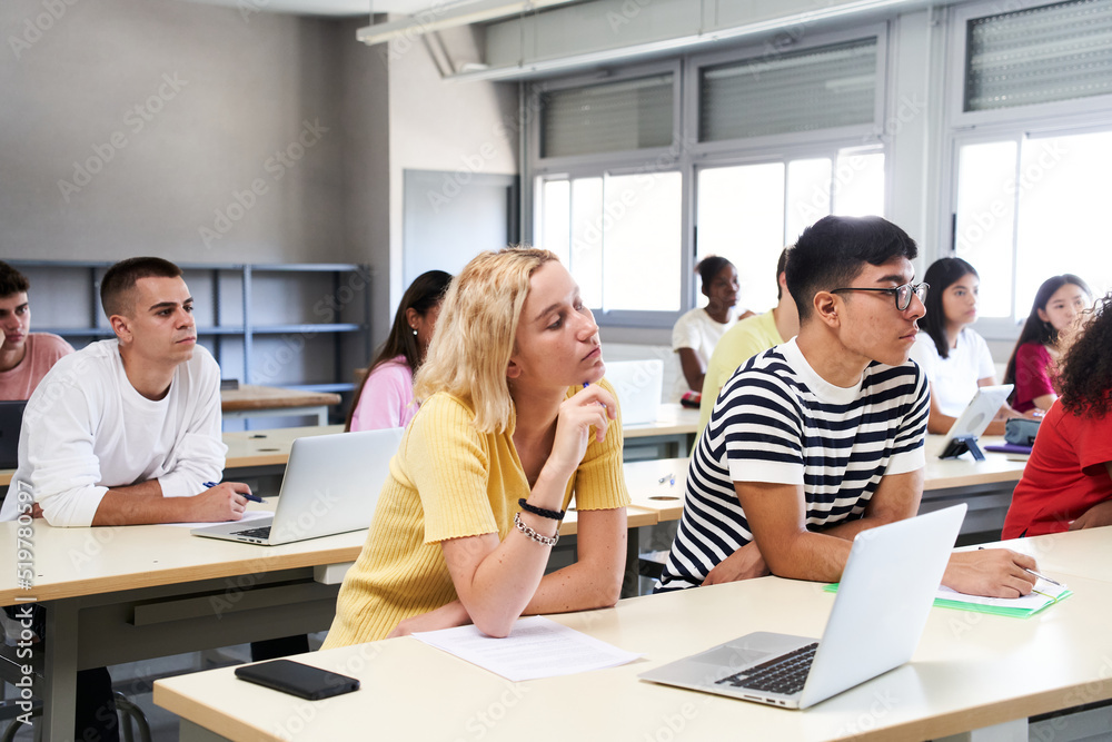 High school science class: A boy and girl using a laptop computer while attending to the teacher in class. Group of students learning in the classroom. High school science class: A boy and girl using a laptop computer while attending to the teacher in class. Group of students learning in the classroom.