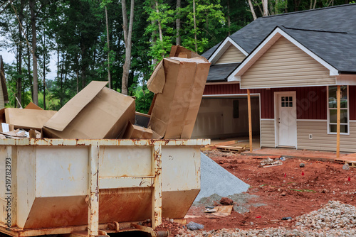 Industrial dumpster filled rubbish removal container on house under building in construction site