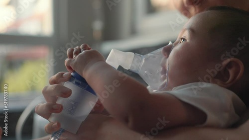 Side view of baby breathing an inhaler at home