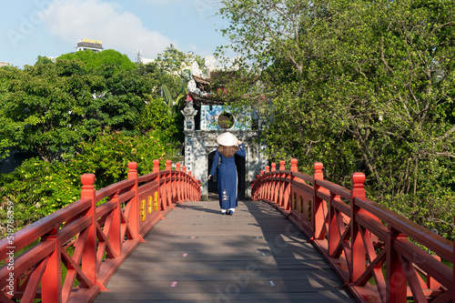 Woman traveller is sightseeing at Huc Bridge spanning Ngoc Son Temple, Hanoi, Vietnam photo