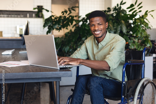 Foto Portrait of smiling african american businessman with disability using laptop in