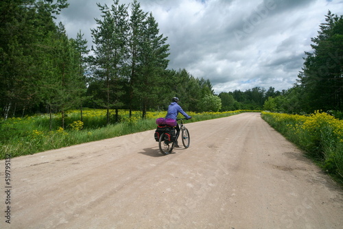 A tourist on a bicycle rides along the road among the blooming fields of Bashkiria, Russia.