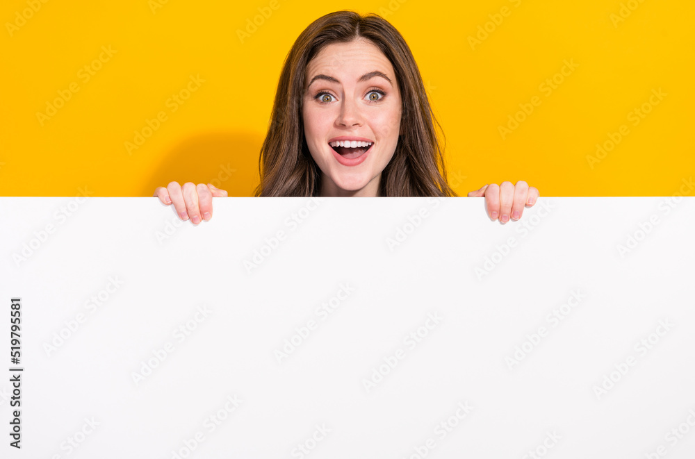 Photo of funky astonished person hide behind empty space blank open mouth isolated on yellow color background Photo of funky astonished person hide behind empty space blank open mouth isolated on yellow color background