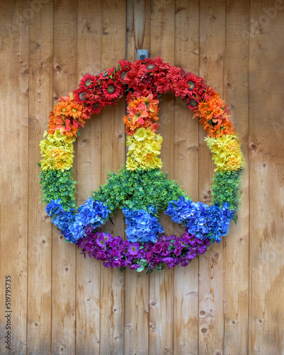 Fotografie, Obraz A colorful peace sign made of multi-colored flowers hangs on a wooden wall in Woodstock, NY
