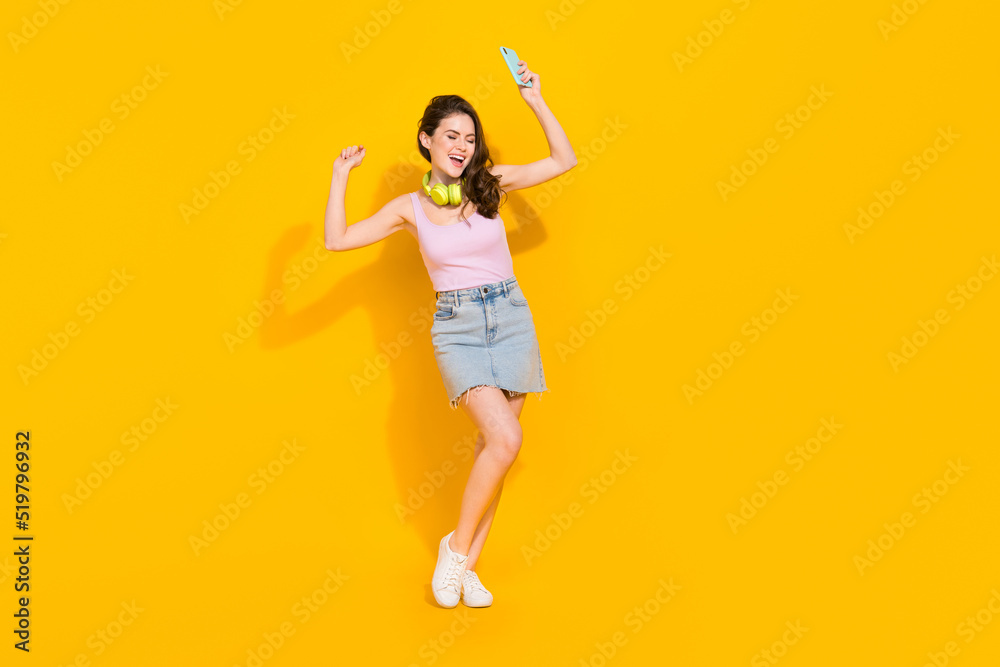 Full body photo of overjoyed satisfied lady hold telephone dancing isolated on yellow color background