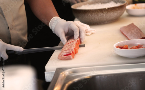 Professional man cut fresh salmon at kitchen of japanese food restaurant.