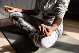 Young african american woman sitting on mat while doing yoga at home