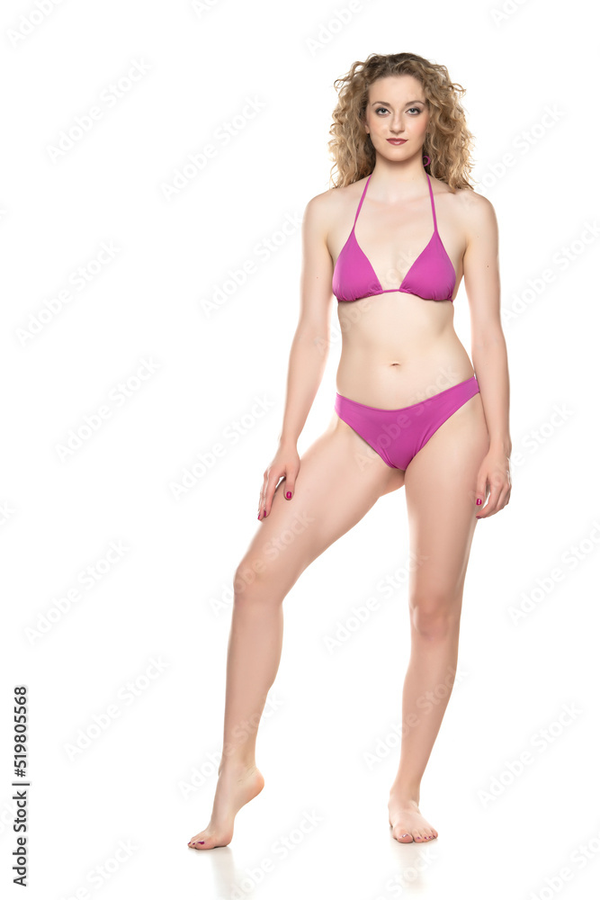 Young blond woman in bikini swimsuit standing on a white background Young blond woman in bikini swimsuit standing on a white background