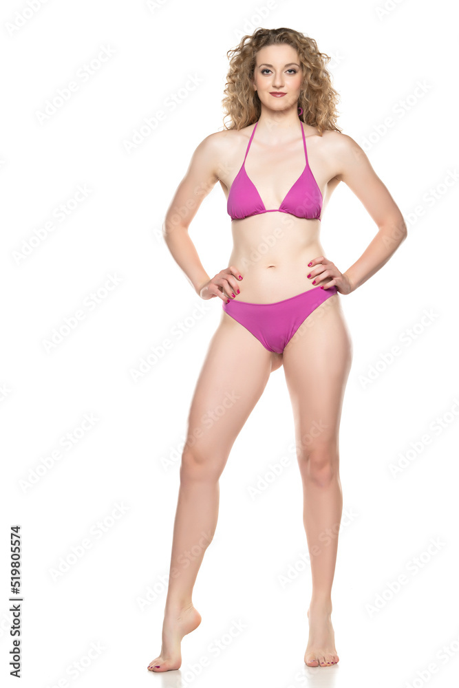 Young blond woman in bikini swimsuit standing on a white background Young blond woman in bikini swimsuit standing on a white background