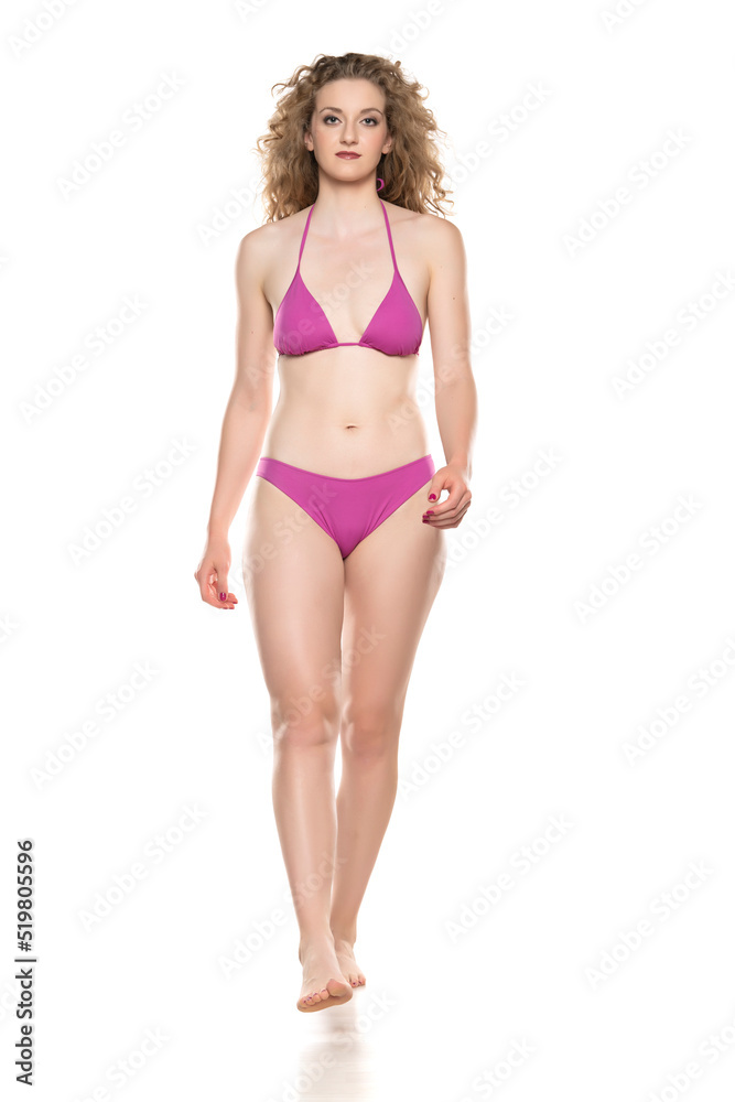 Young blond woman in bikini swimsuit walking on a white background Young blond woman in bikini swimsuit walking on a white background