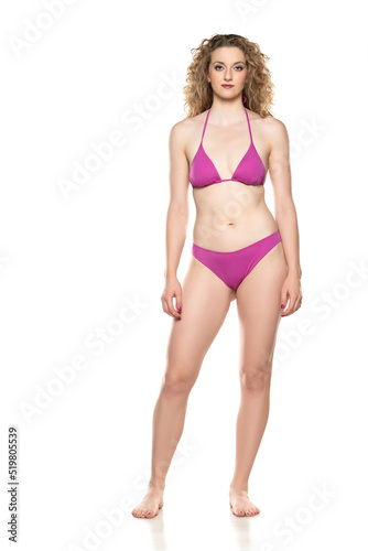 Young blond woman in bikini swimsuit standing on a white background
